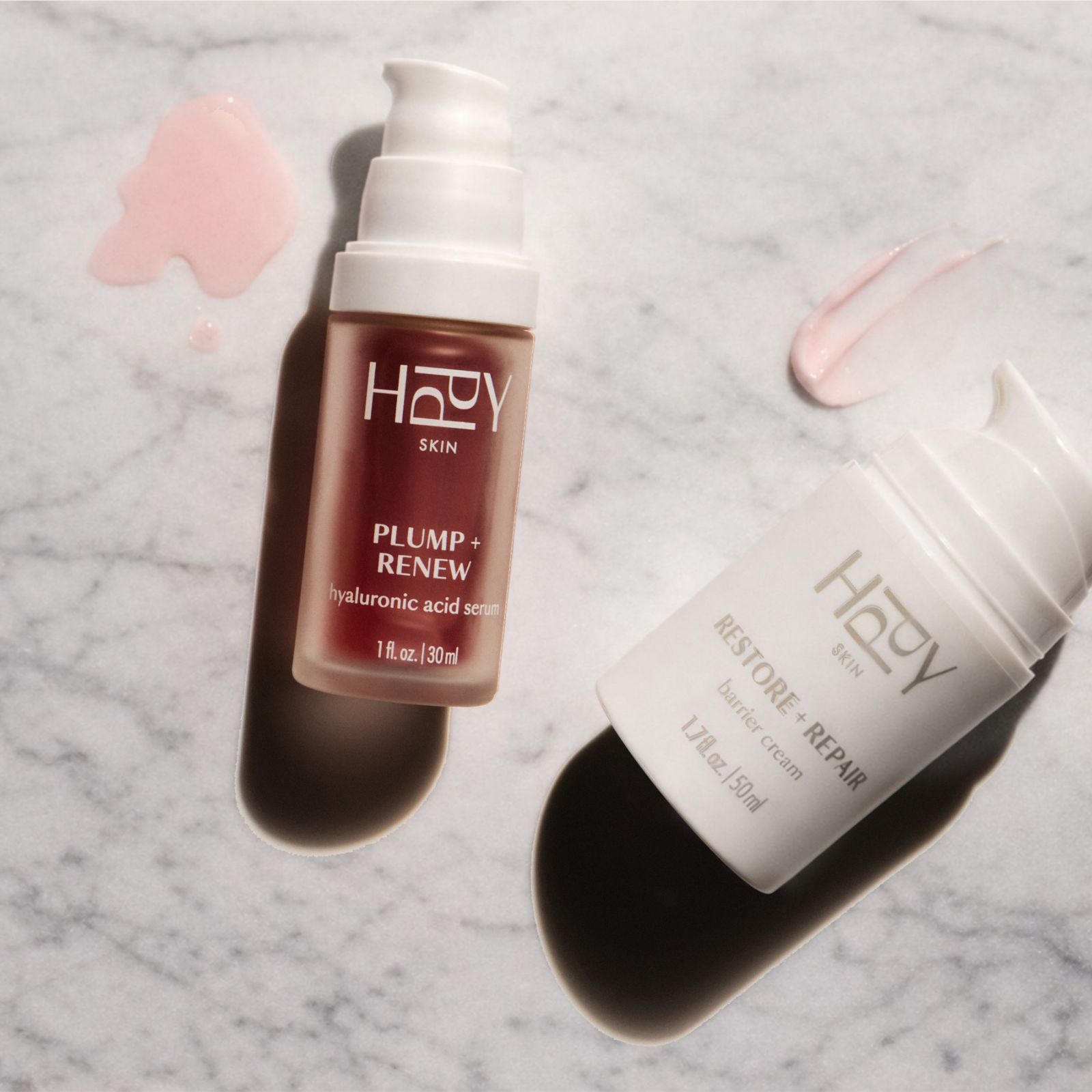 Two skincare products from the brand 'HPPY' on a marble surface.