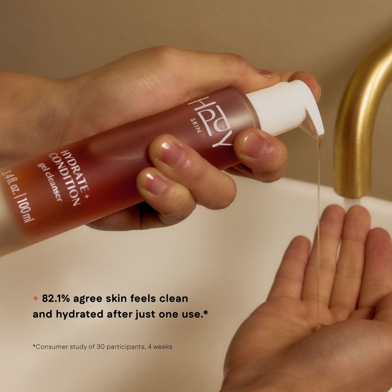 Hand holding a bottle of skincare product over a sink with water flowing.
