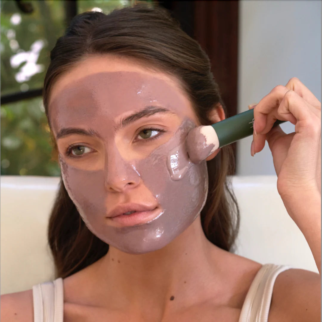 Woman applying a facial mask with a brush outdoors