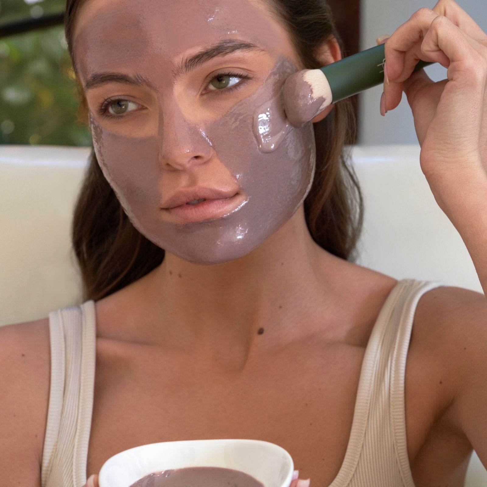 Woman applying a facial mask to her face with a brush