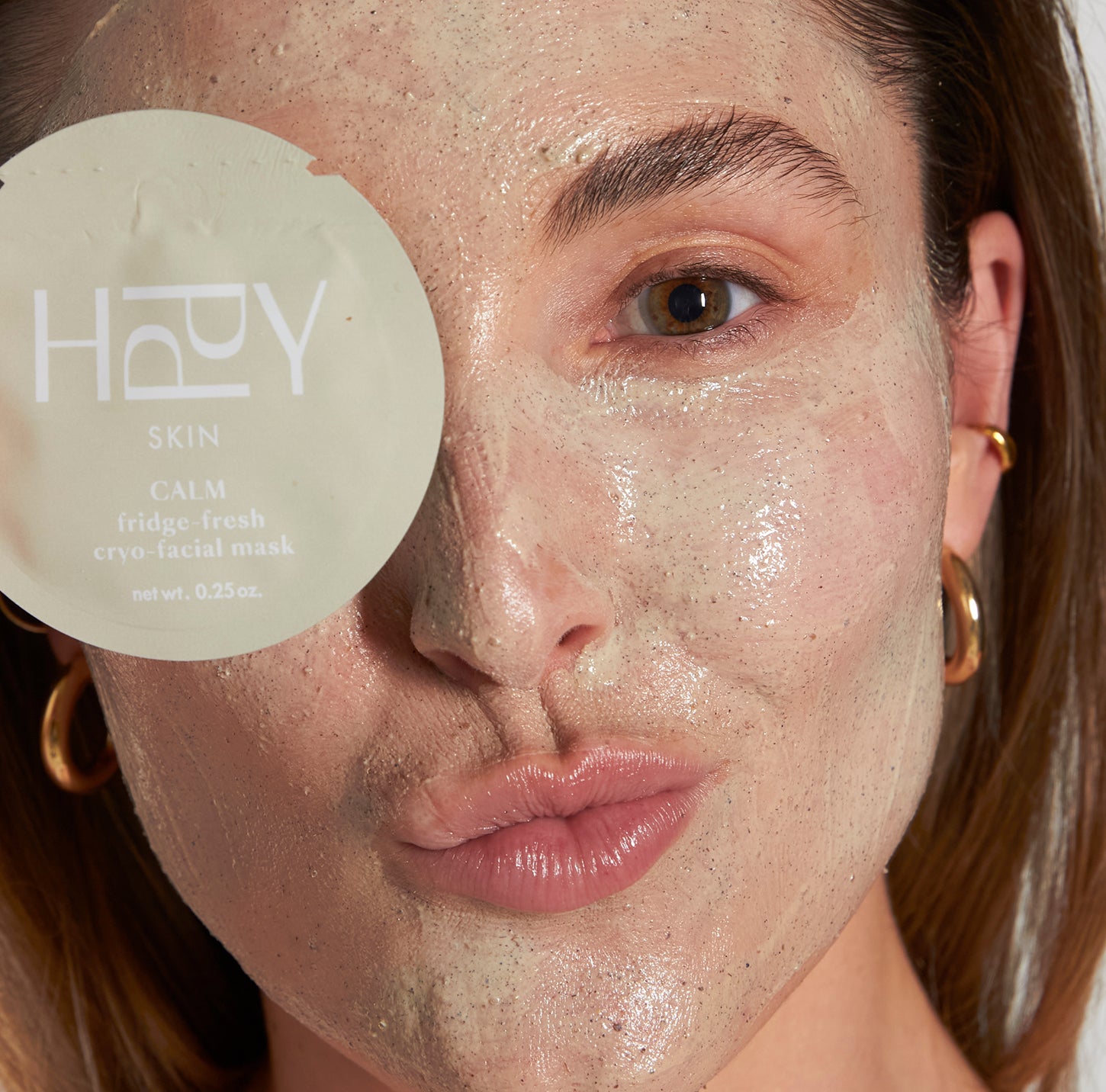 Woman applying a facial mask with a 'HAPPY SKIN' product in the foreground.