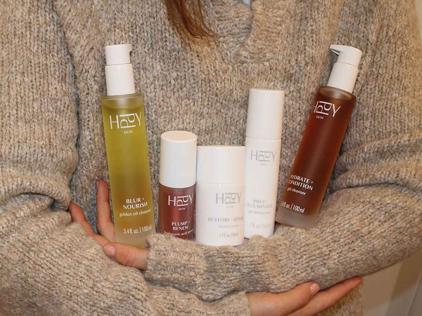 Person holding a collection of HPPY skincare products.