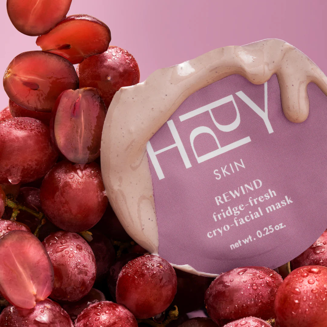 Happy Skin rewind fridge-fresh cryo-facial mask surrounded by red grapes on a pink background
