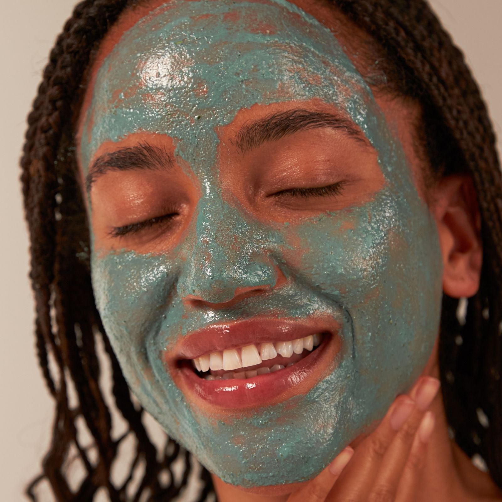 Person with a blue facial mask on their face against a neutral background