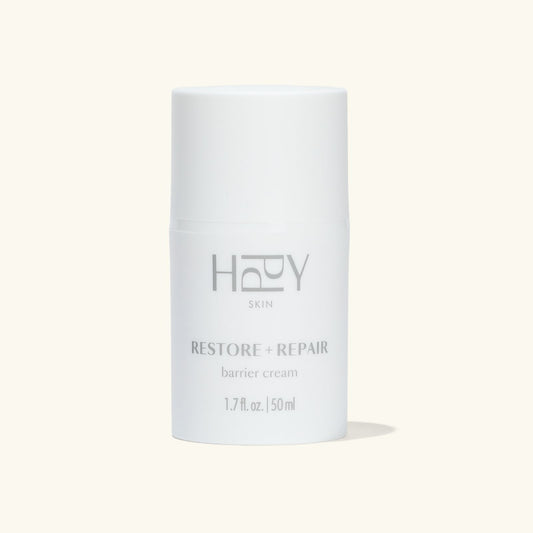 White cylindrical container of HPPY Skin Restore + Repair barrier cream on a light gray background