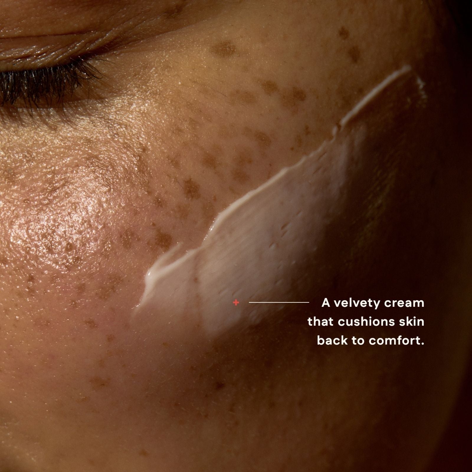 Close-up of skin with a line of cream applied, labeled 'A velvety cream that cushions skin back to comfort.'