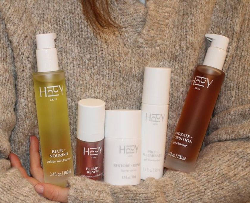 Five bottles of HPPY skincare products on a textured surface