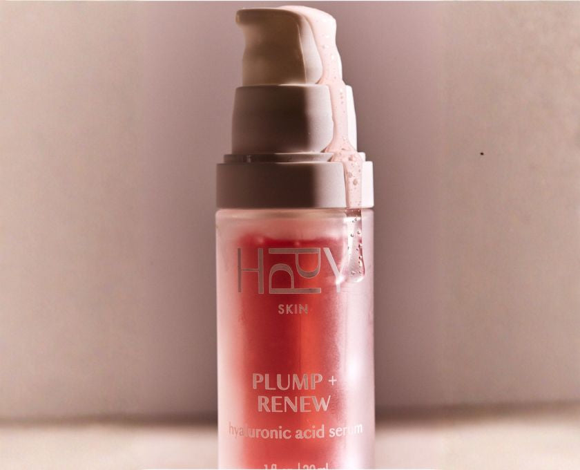 Pink serum bottle with pump on a beige background