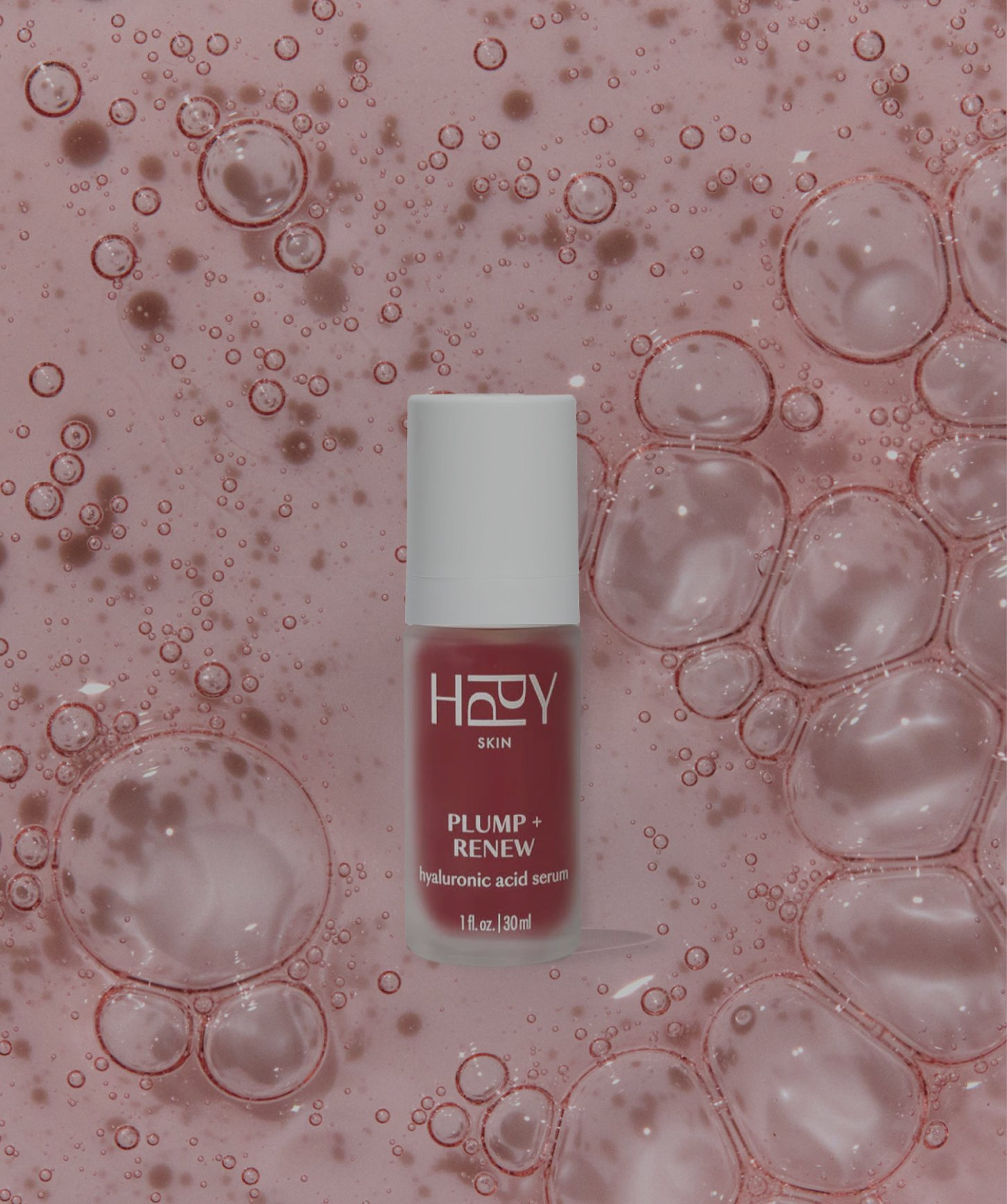 Skincare serum bottle labeled 'HPPY Skin' on a pink background with bubbles