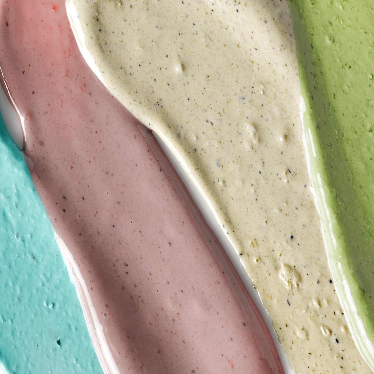 Close-up of three different colored sauces on a textured surface