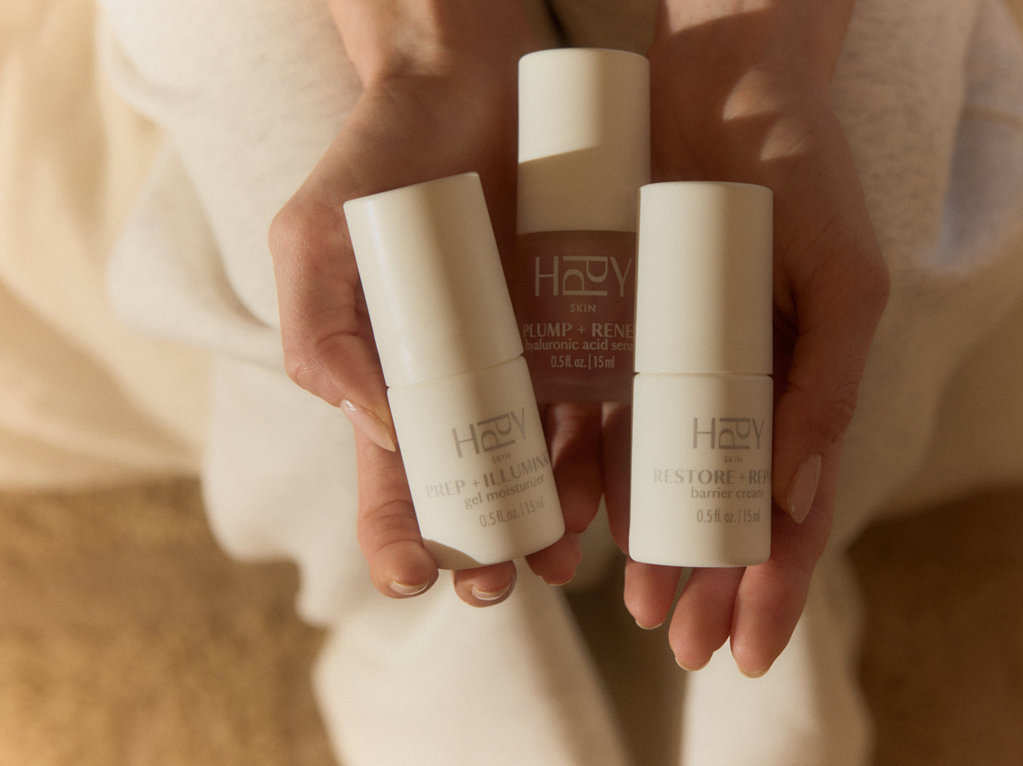 Three skincare products held in hands against a neutral background