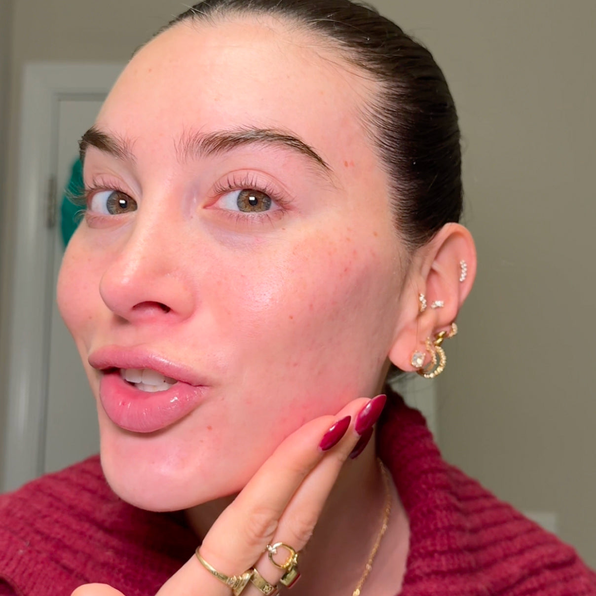 Woman adjusting an earring with a neutral background