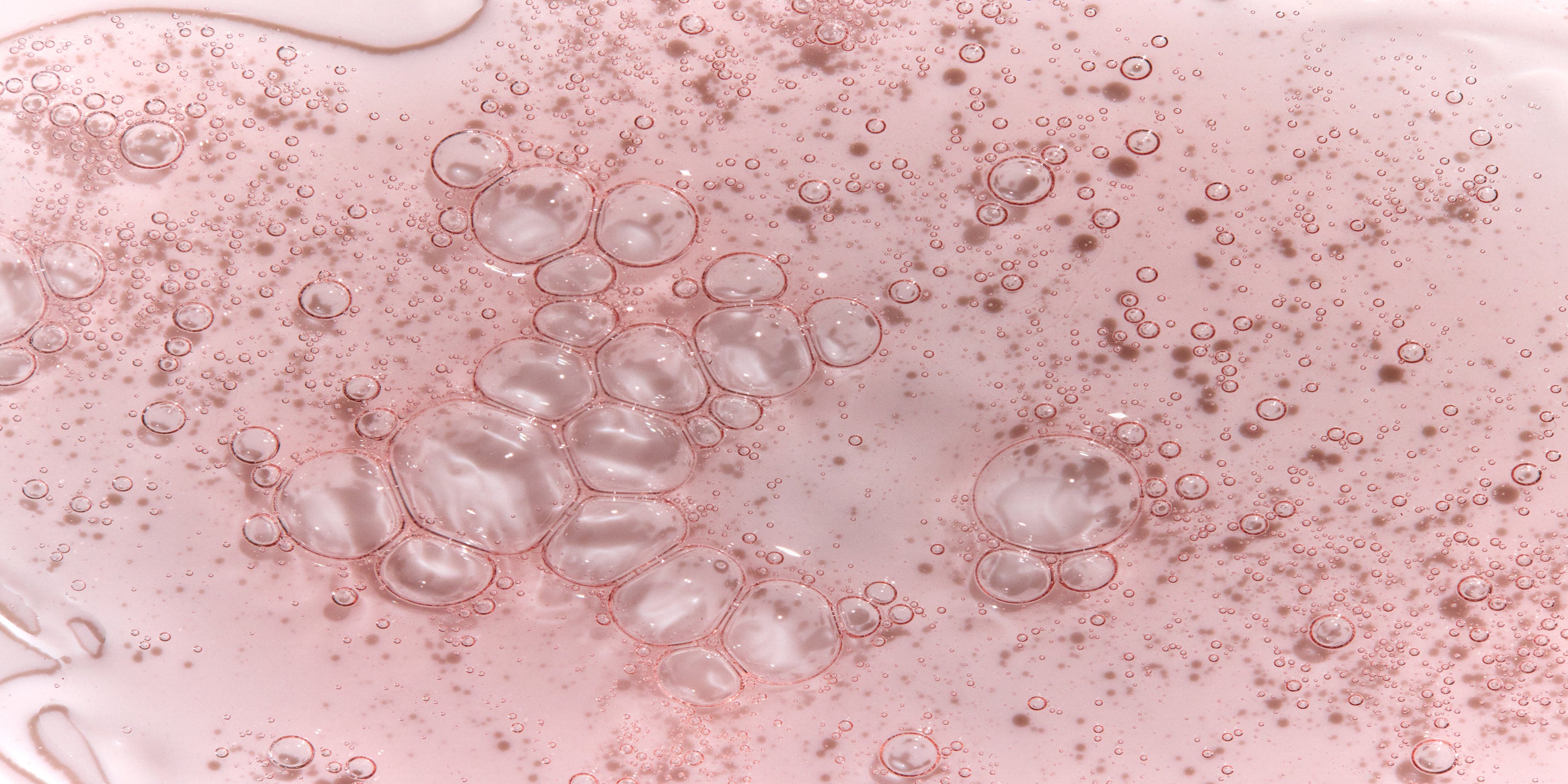 Close-up of pink liquid with bubbles on a white background
