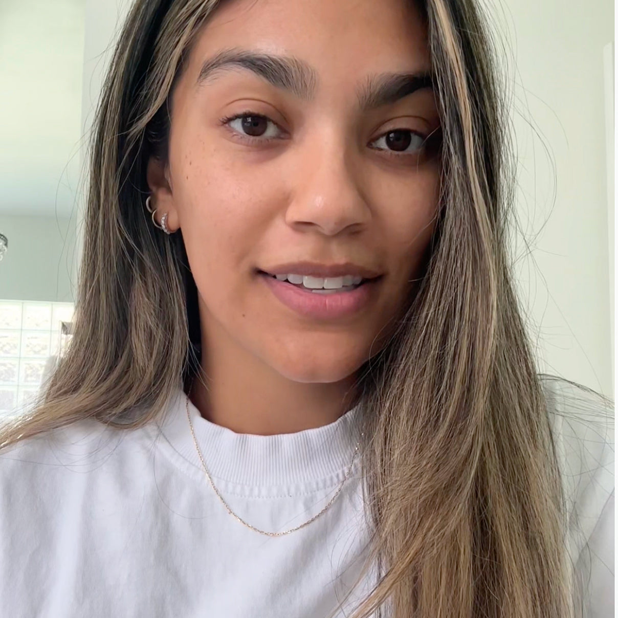 Close-up of a person with long hair wearing a white shirt indoors.