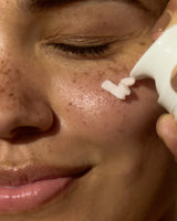 Person applying cream to their face with a small applicator