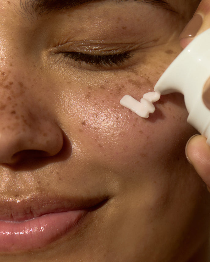 Person applying cream to their face with a small applicator