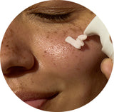 Close-up of a person using a white tool on their face.