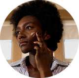 Woman with an afro, wearing a striped shirt, in a close-up shot.