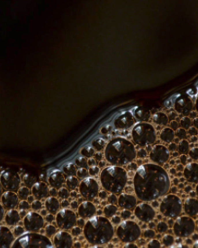 Close-up of a dark liquid with bubbles on a dark background