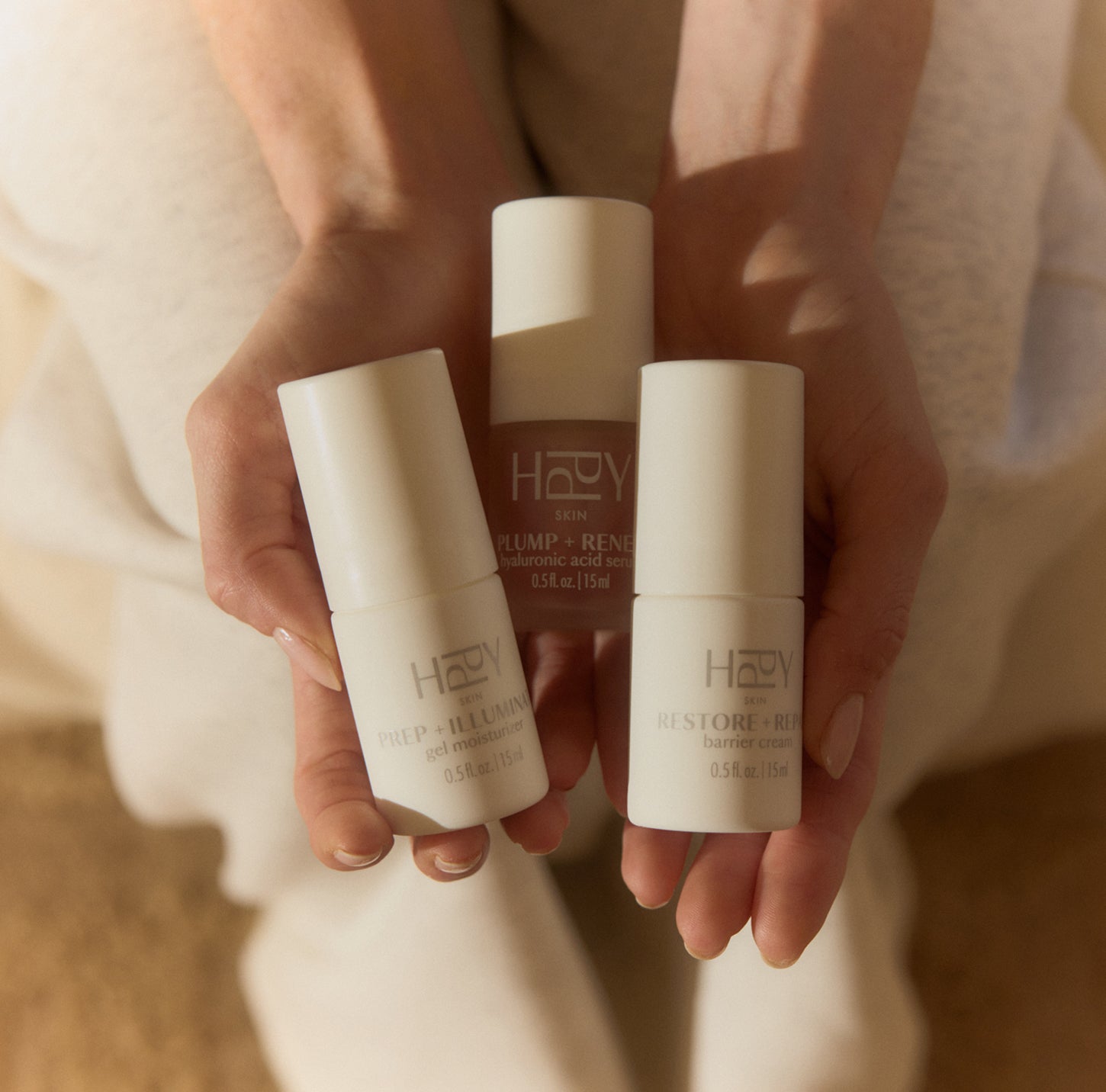 Three skincare products held in hands with a neutral background